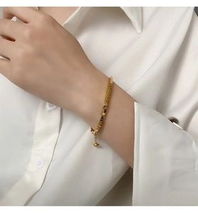 Detail of a gold square link titanium steel bracelet worn on a female wrist with a white shirt