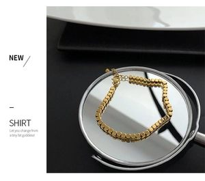 Detail of gold cube bead bracelet with adjustable lobster clasp on mirror reflection