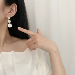 Three-layer geometric gold earrings with mother of pearl and pavé crystals on a model