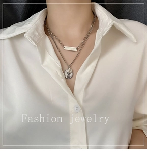 Close-up of double layer silver titanium necklace with portrait coin and square pendant