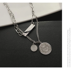Detail of layered titanium steel necklace with engraved rectangle and coin pendants