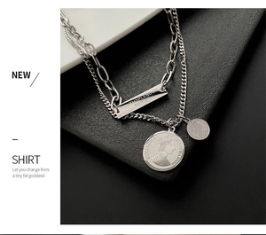 Macro detail of silver layered titanium necklace with coin and engraved plaque pendants