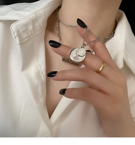 Detail of layered silver necklaces with vintage coin pendants and a gold ring