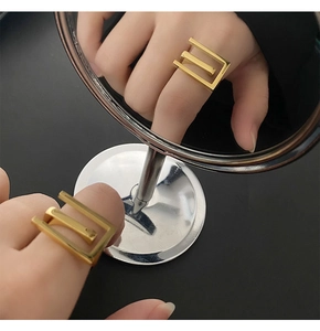 Macro view of gold minimalist triple band geometric ring shown in a mirror reflection
