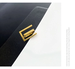 Detailed view of layered geometric gold ring on a minimalist black and white background