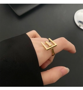 Macro view of geometric triple-line gold-plated ring showing minimalist hollow structure