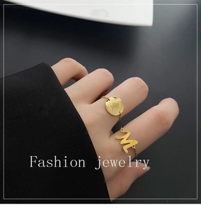 Détail de bagues chaînes dorées avec pendentif pièce et breloque lettre M à la main
