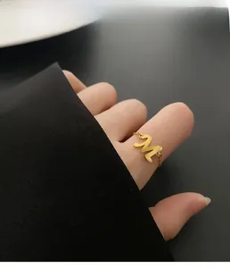 Détail d'une bague chaîne dorée avec un design élégant de lettre M sur le doigt d'un mannequin