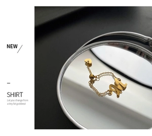Détail d'une bague chaîne dorée réglable avec pendentif lettre M et petit cœur