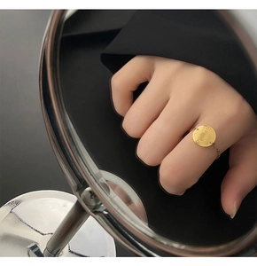 Détail macro d'une bague chaîne en or avec pièce Reine Elizabeth II sur surface miroir