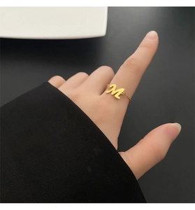 Gros plan d'une bague chaîne en or avec motif lettre M portée au doigt