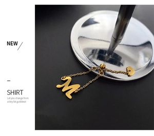 Détail du pendentif lettre M dorée et petit cœur avec une fine chaîne en métal doré