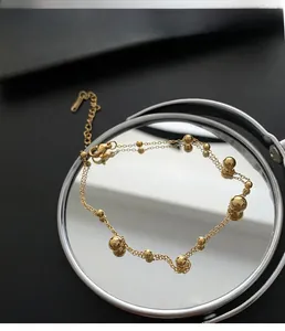 Close-up of double-layered gold bead bracelet with adjustable lobster clasp on mirror