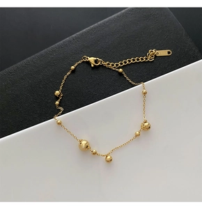 Close-up of minimalist golden bead chain with lobster clasp and adjustable extension link