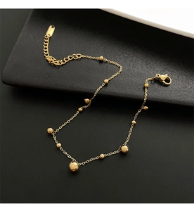 Detailed close-up of golden beaded anklet with lobster clasp and adjustable extension chain
