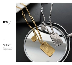 Detail of square titanium steel necklaces with Good Luck charms and engraved messages