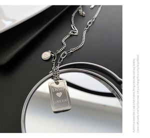 Detailed shot of engraved silver pendant with Dear Love You and Good Luck charms