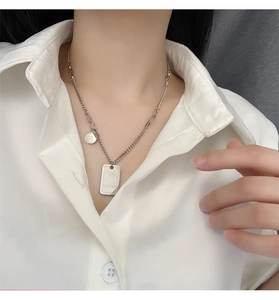 Detail view of silver titanium necklace with square pendant and Good Luck round tag