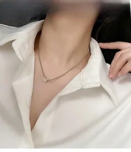 Dettaglio della collana in acciaio al titanio con pendente a cubo indossata da modella