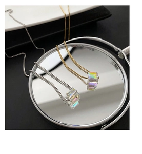 Dettaglio della collana in titanio con ciondolo a cubo iridescente e riflesso specchiato