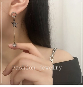 Detail of long star tassel earrings with crystal studs and chain on a female model