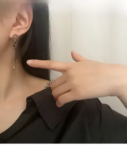 Detailed view of silver star tassel earrings worn by a model in a minimal setting