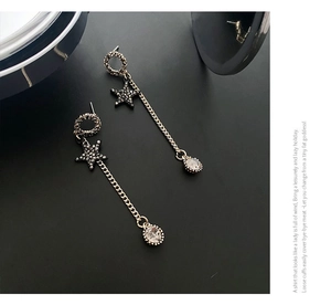 Detail of long gold tassel earrings with black star charms and teardrop crystals