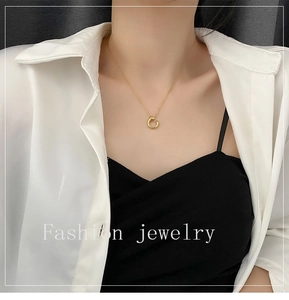 Detail of a minimalist gold geometric circle necklace on a delicate chain around the neck