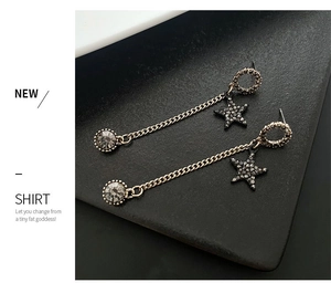 Detail of long gold tassel earrings featuring black star motif and gray gemstone drop