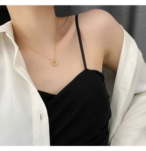 Detail of a minimalist gold geometric circle necklace on a neck with a white shirt
