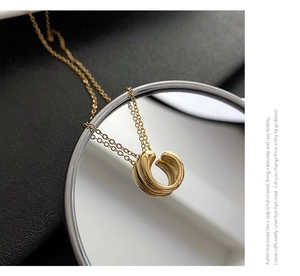 Polished gold geometric circular necklace shown on a reflective mirror background