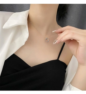 Close-up of a minimalist silver geometric circle pendant necklace worn by a fashion model