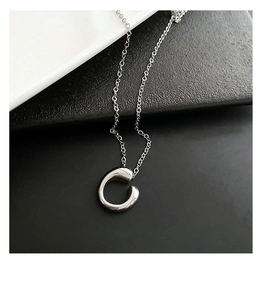 Macro shot of minimalist geometric C-shaped pendant with high-polished silver finish