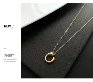 Macro shot of polished gold geometric circular pendant on a fine link chain necklace