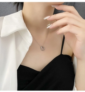 Detail of silver U-shaped geometric pendant on cross chain worn by a model