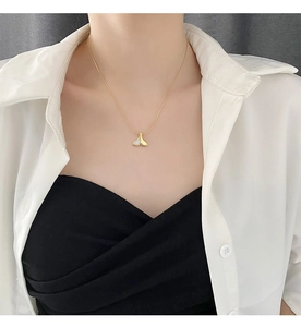 Dettaglio della collana con coda di sirena dorata e madreperla bianca indossata dal modello