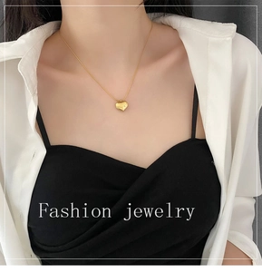 Detail shot of a polished gold heart pendant necklace on a model with elegant styling