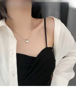 Close-up of a silver heart pendant necklace on a model showing refined mirror finish