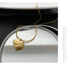 Detail of gold heart pendant with mirror finish and sleek snake chain for women