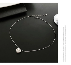 Detailed view of polished silver heart pendant necklace with sleek snake chain and lobster clasp