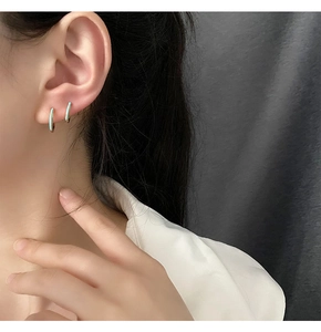 Primer plano de pendientes de aro dorados con esmalte azul claro en una modelo