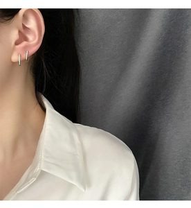 Detalle de pendientes de barra dorados con esmalte azul claro en una modelo