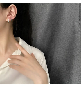 Primer plano de pendientes de aro minimalistas de acero de titanio plateado