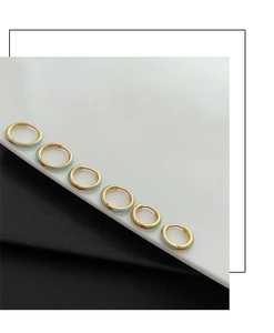 Detalle de seis pendientes de aro dorados con esmalte azul claro sobre fondo bicolor