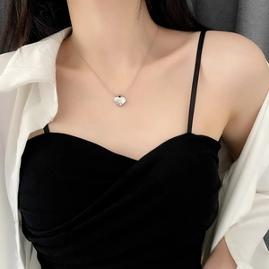 Elegant silver heart pendant necklace on minimalist chain worn by a model in close-up