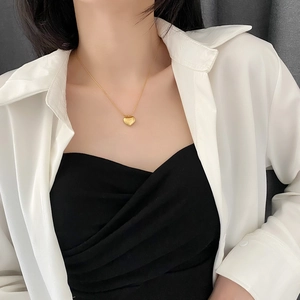 Elegant gold heart pendant necklace for women worn with a classic white shirt
