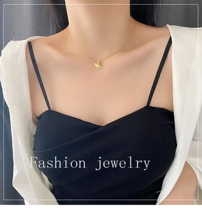 Close-up of golden ginkgo leaf pendant necklace worn by a model on a minimalist background