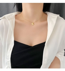 Detail of a gold ballerina pendant necklace crafted in titanium steel on model