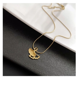 Detailed close-up of a golden ginkgo leaf pendant with fine texture on a bicolor background