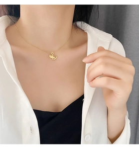 Close-up of golden ginkgo leaf pendant necklace worn on a woman's collarbone